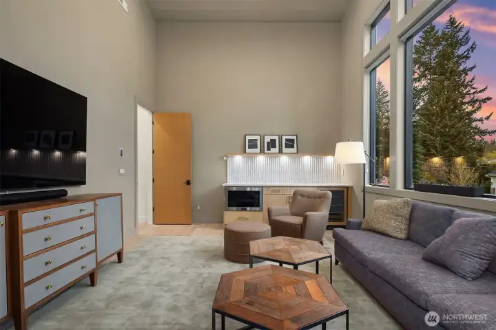 A vaulted bonus room with soaring ceilings, a built-in wet bar, and a wall of windows. Media room, playroom, second living space — it works equally well as all three.