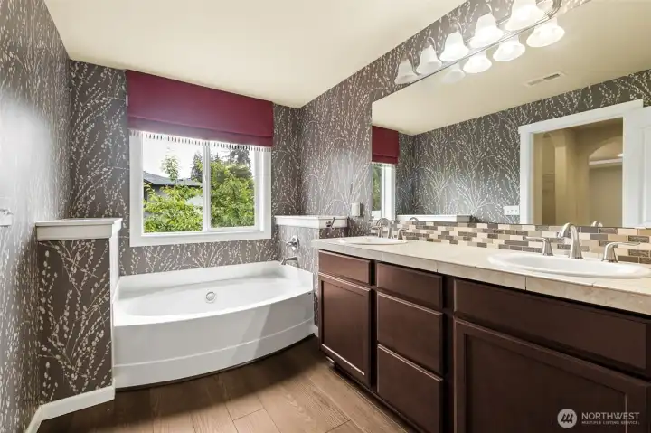 Large primary bath w/beautiful wall paper, large soaking tub under the window, two sinks in large cabinet and engineered floor. Large primary bath w/beautiful wall paper, large soaking tub under the window, two sinks in large cabinet and engineered floor.