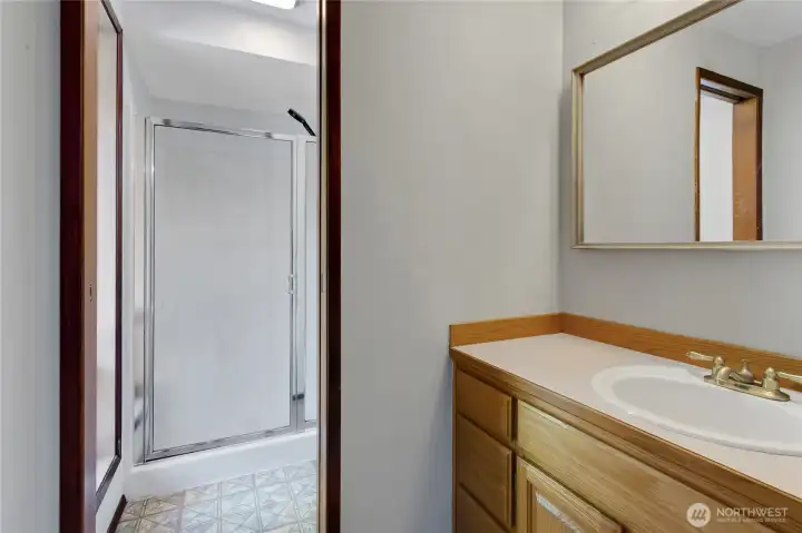 Private bath serving the primary suite includes walk in shower, toilet ad vanity.