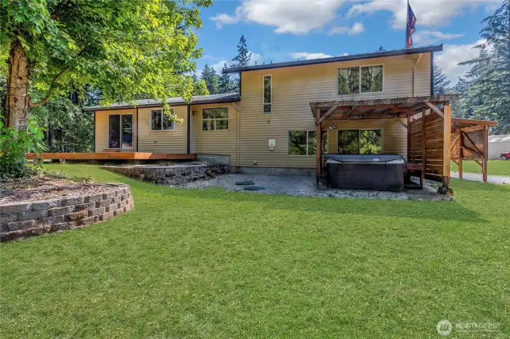 Private backyard setting featuring a brand-new deck and covered hot tub area, ideal for year-round relaxation and entertaining in a peaceful, secluded environment. Grass digitally enhanced to show potential. See aerial View