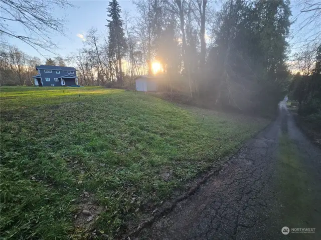 Looking across the lot from Sipes Lane towards the newly build neighbor home.  short green metal posts are the staked-out house perimeter. Everything is here and ready to go for your plan!