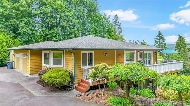 Charming home boasts a spacious deck, perfect for outdoor entertaining and enjoying the serene, tree-filled surroundings. The property features an attached two-car garage, RV parking and storage.