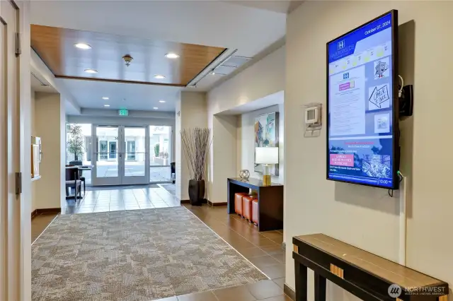 Secure Lobby, with mailboxes on the left, and a community update digital screen on the right.