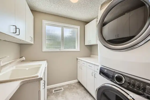 The utility room features new vinyl flooring, a laundry tub and abundant cabinet and counter space.