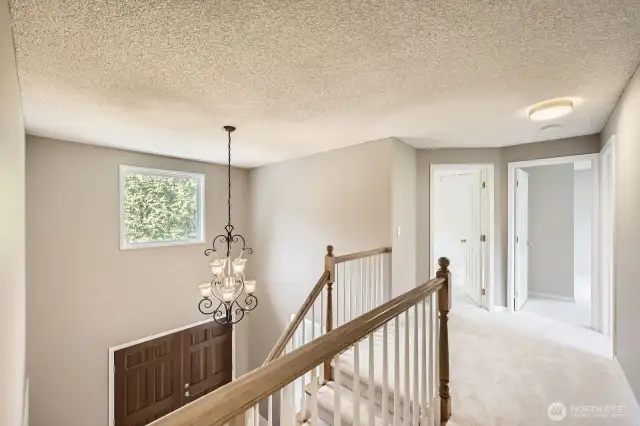 The landing of the two-story staircase overlooks the foyer and the elegant chandelier with plenty of light pouring in from the window above.