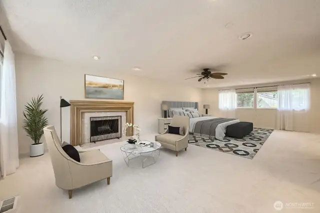 A different perspective of the spacious Primary Suite with a sitting area in front of an attractive fireplace, brand new carpet, ceiling fan and a great deal of natural light.