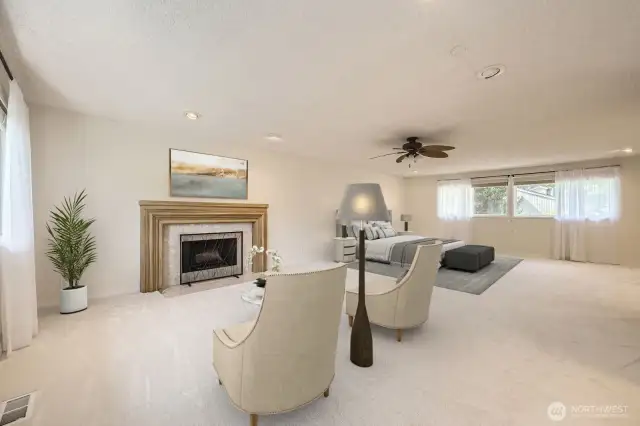 A different perspective of the spacious Primary Suite with a sitting area in front of an attractive fireplace, brand new carpet, ceiling fan and a great deal of natural light.