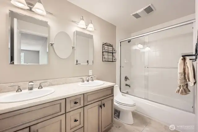 You will enjoy the space of the guest bathroom with dual sinks, abundant light, bathtub and marble terrazzo tile floors.