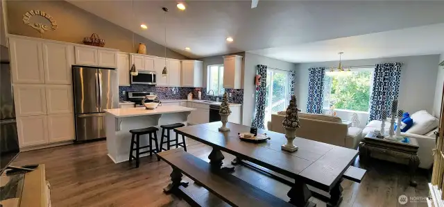 Bask in the light-filled elegance of this open-concept living, dining, and kitchen space—where canal views take center stage. Crisp white cabinetry, stainless steel appliances, designer glass tile backsplash and a spacious island invite easy entertaining, while the warm wood tones and panoramic windows blend coastal charm with everyday comfort. A perfect layout for soaking in Surfside serenity, indoors and out.