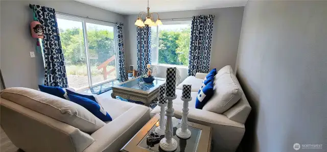 Warm and inviting, this stylish canal-side living room pairs elegant furnishings with abundant natural light and tranquil views. The soft neutral palette is accented by bold blue details and graceful touches like a candlelit side table and classic chandelier—creating a refined coastal space with effortless indoor-outdoor flow