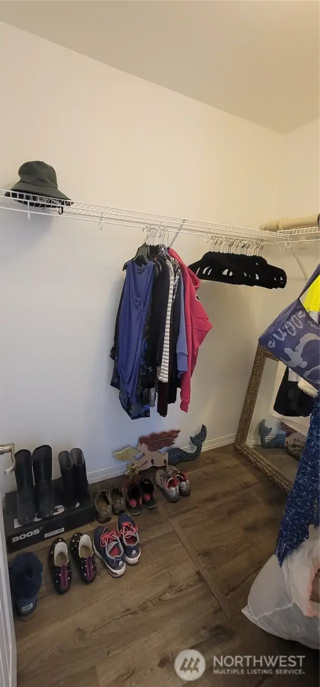 Organized and spacious, the walk-in closet in this primary bedroom offers functional style with plenty of room for wardrobes, shoes, and accessories. Warm  floors and custom shelving make it both practical and inviting—perfectly complementing the ease of Surfside living.