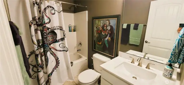 Bright and beachy with whimsical flair, this guest bathroom features a full tub and shower combo, and clean, coastal finishes. Thoughtful touches create a welcoming space that’s both functional and full of personality.