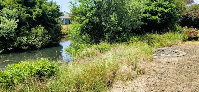 Nestled beside a serene stretch of canal, this lush coastal sanctuary offers natural beauty just steps from your door. The low-maintenance landscaping frames a peaceful waterside view, while a private firepit area invites evenings spent under the stars in pure Surfside tranquility.