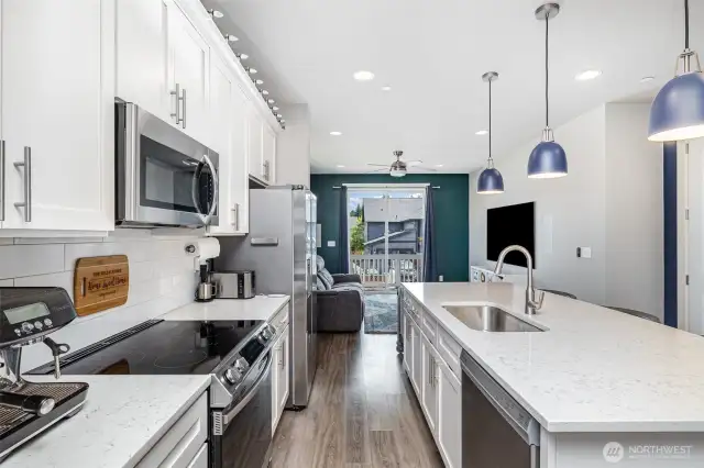 Light, bright, and open kitchen showcases quartz countertops, stainless steel appliances, a spacious island with sink, and seating—perfect for cooking and gathering.