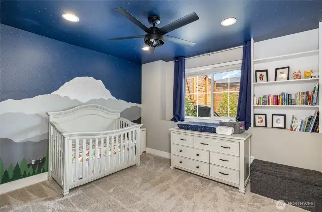 Charming downstairs guest bedroom showcases a custom mountain mural, ceiling fan, recessed lighting, and built-in shelving—perfect blend of style and function.