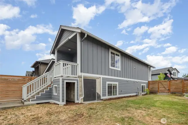 Fully fenced backyard features a built-in playhouse or storage area tucked neatly under the back patio stairs—perfect for fun or functionality.