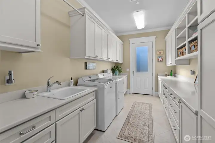 Large utility room with sink, exterior entrance, and lots of cabinets.  W/D space has hook-ups for both gas and electric.