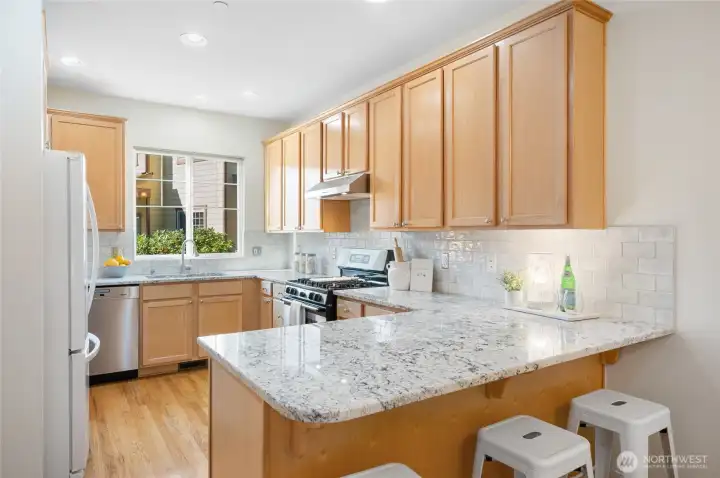 Chef’s kitchen featuring slab granite countertops, full-height backsplash, and slide-out drawers inside cabinets.