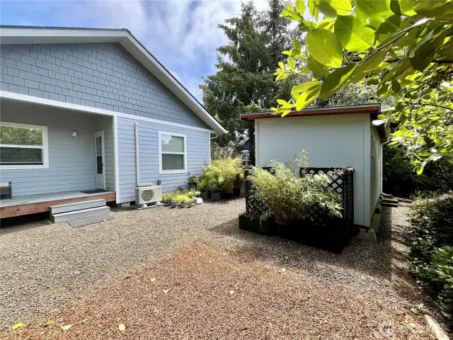 View of the walk-in storage shed, back of home and Mini Split Heater/ AC unit by the deck steps