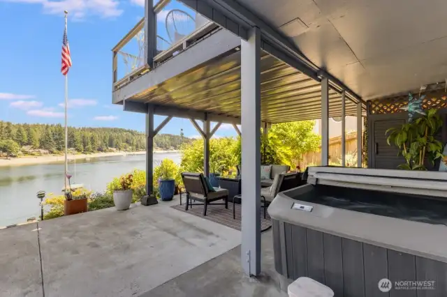 Covered patio area on the lower level with hot tub, sauna, and outdoor shower