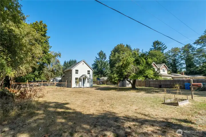 Spacious front lot framed by mature trees, offering a glimpse of the home’s orchard roots and plenty of space for outdoor living or future projects