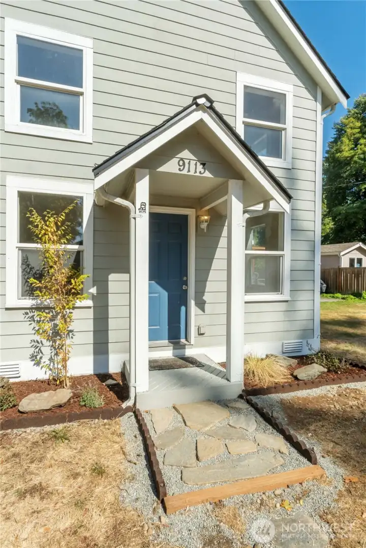Inviting entryway with fresh stone pathway and charming covered porch, a thoughtful touch that blends history with everyday convenience.