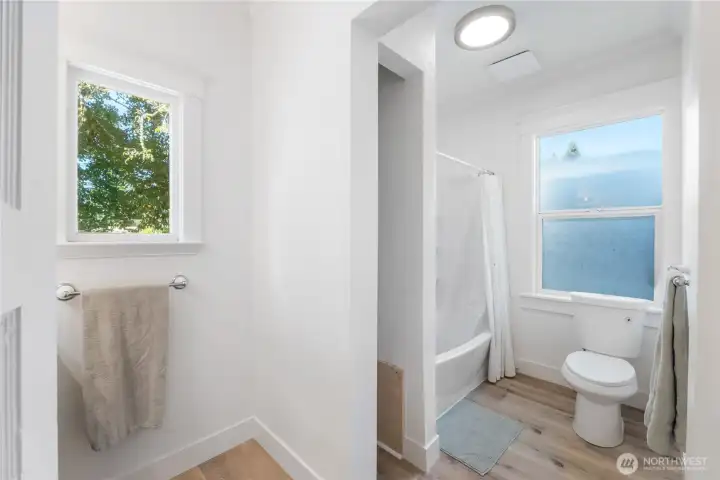 Bright and functional, this full bathroom offers a blend of historic simplicity and modern updates. A window above the tub brings in natural light, while crisp finishes and thoughtful design ensure comfort and convenience.