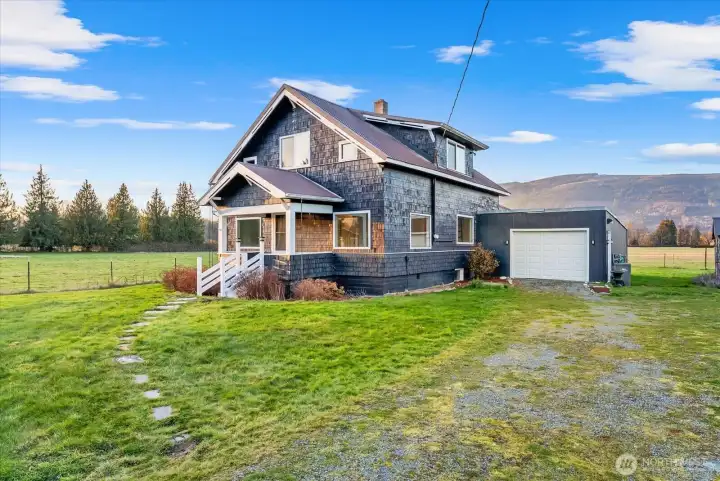 Charming 1920s farm home has refreshed exterior paint, native growth landscape, and abundant space for parking, featuring a gravel horseshoe driveway providing easy access. The property backs onto a Seattle City Light-owned lot, offering privacy and a chance to see elk roaming from your back porch.