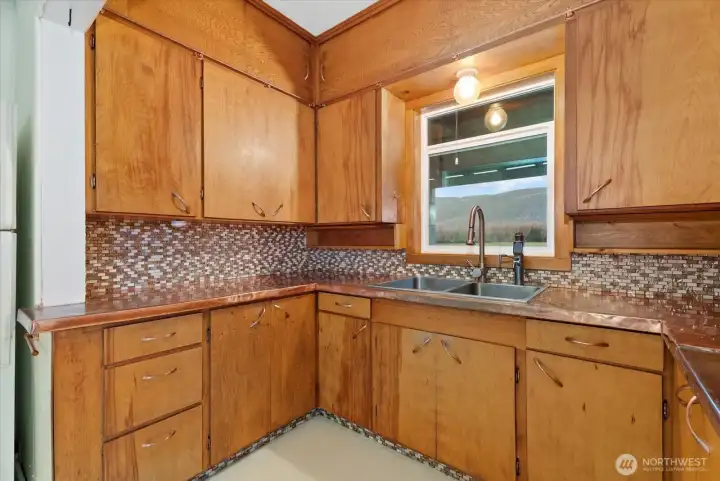 Recently updated custom copper countertops, beautiful glass tile, and a designer sink and faucet enhance the farmhouse charm of the kitchen.