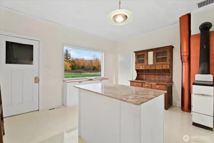 Providing both functionality, beauty and flow, the kitchen offers garage access, ample storge options, classic early 1900s features, and picturesque views from the over-sized window.