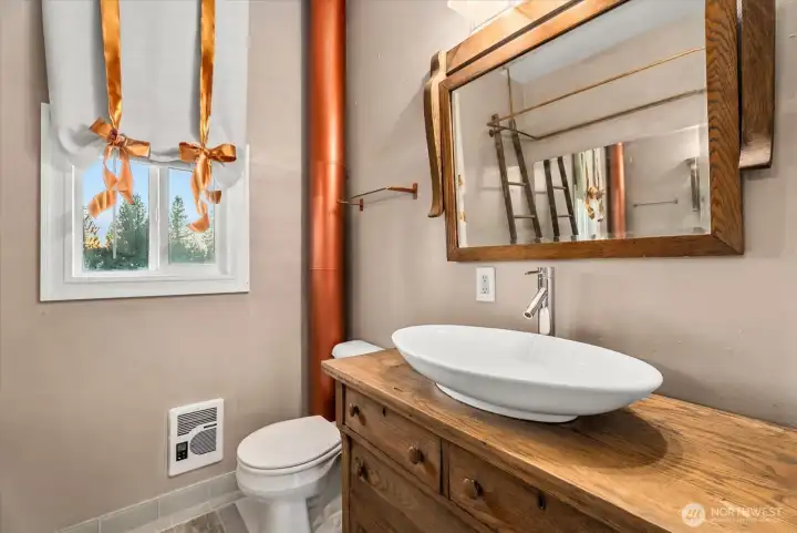 Updated main level bathroom with new tile floors, solid-wood vanity, and copper accents.