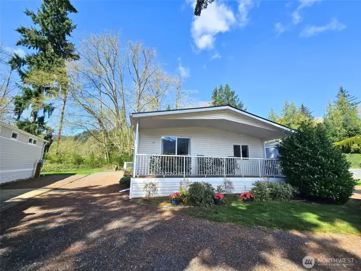 Wide exterior view showing the home’s setting, parking, and surrounding landscape
