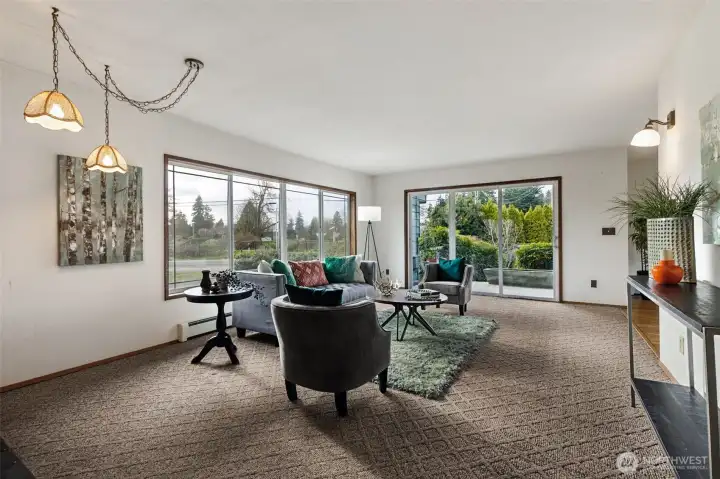 This living room boasts views of the mature landscaping and rural neighborhood. There is a rock-wall fireplace with wood-burning insert to the left (not in this photo). The sliding glass door leads to a lovely covered patio. The patio wraps around to the back of the home with built-in concrete planters, terraced mature landscaping. The combination of the entire space is perfect for relaxation or entertaining.