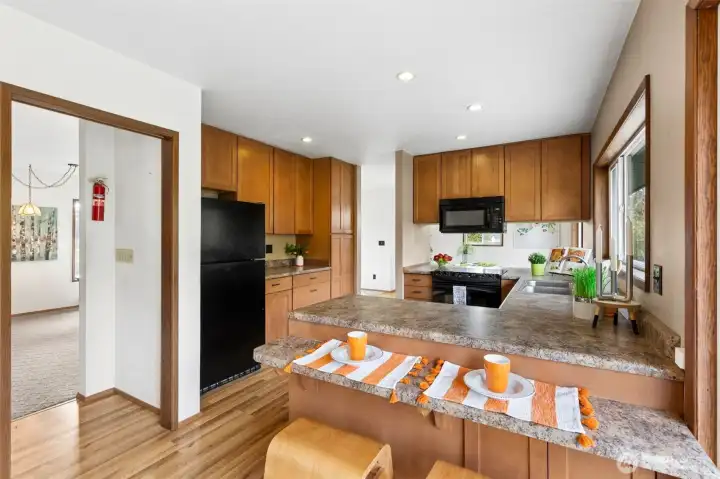 The kitchen offers ample storage & counterspace with a sweet breakfast bar, window looks out to the back side of the home. The pass-through on the left leads to the living room and the stairway to the bedrooms. There is a sliding glass door on the right that leads you to a patio, terraced garden beds and the back yard. The back yard is partially fenced. From the breakfast nook, there are also stairs that lead down to the main level.