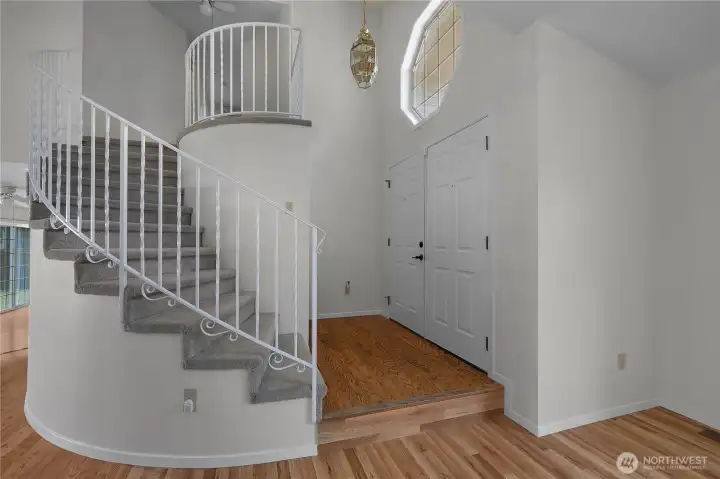 Welcome guests into a bright entry with soaring ceilings, curved staircase, and fresh interior paint.