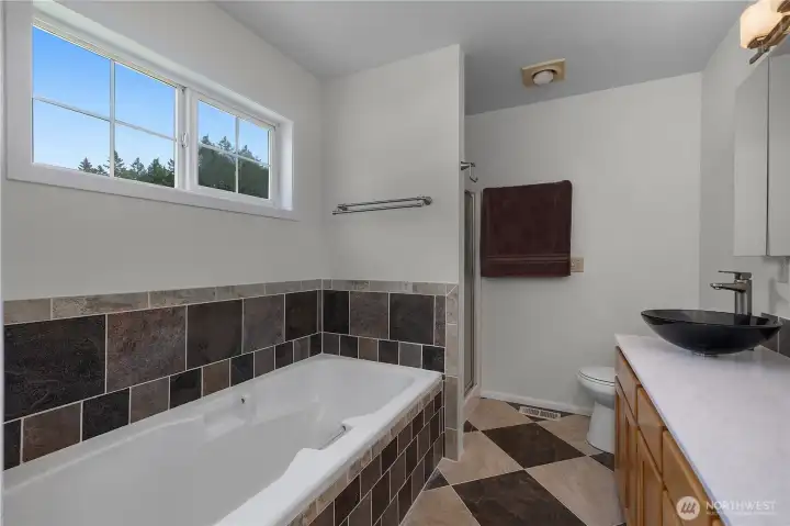 Unwind in the primary bath with soaking tub, tiled surround, and separate shower area.