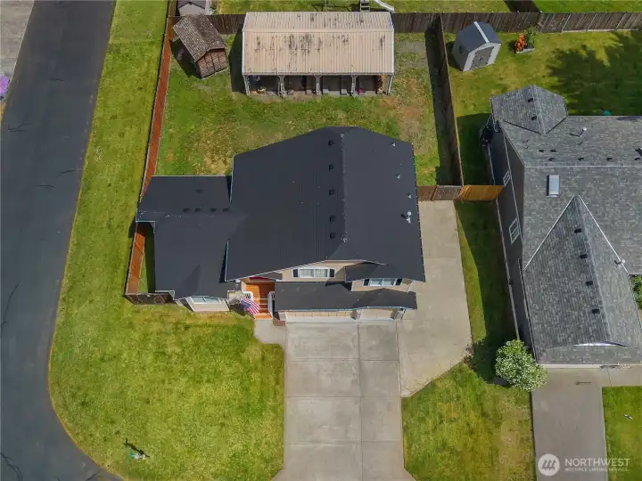 Overhead aerial view showing the new roof, driveway, fenced yard, and detached carport.