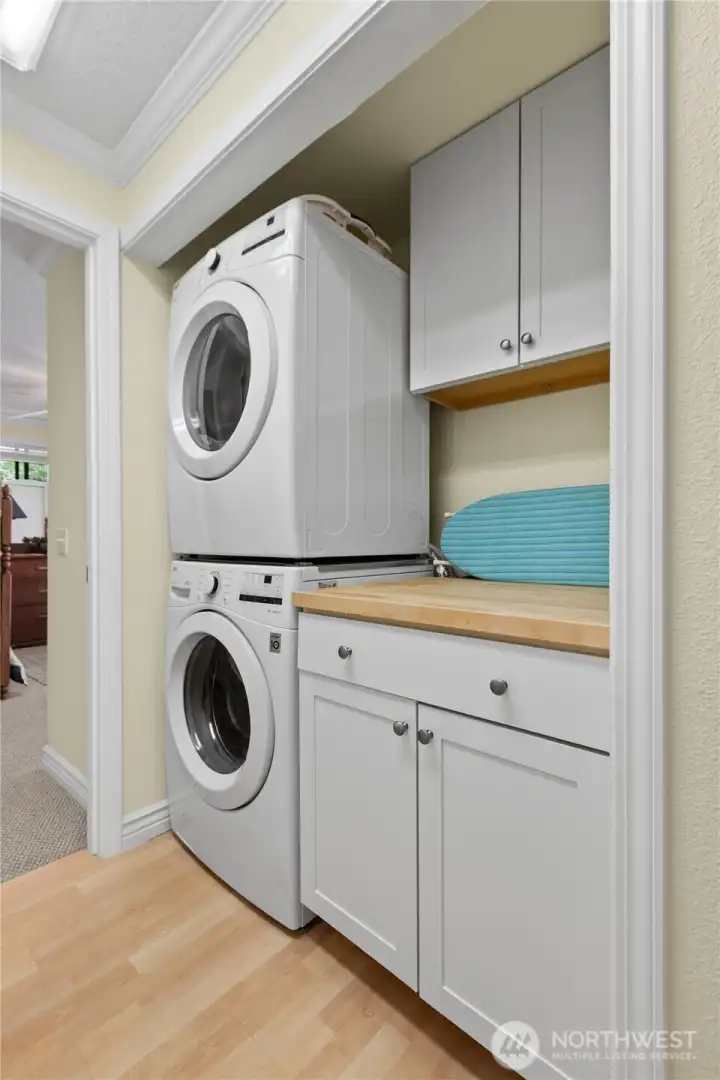 Dedicated laundry area with stacked washer and dryer, added cabinetry, and countertop workspace for everyday convenience. Dedicated laundry area with stacked washer and dryer, added cabinetry, and countertop workspace for everyday convenience.