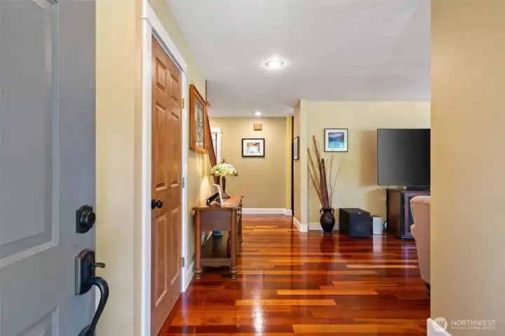 Step inside to a bright and welcoming foyer that immediately showcases the home's quality craftsmanship. Gleaming, rich hardwood floors stretch out before you, guiding the eye past a convenient entry nook down the central hallway, while offering a sneak peek into the spacious main living spaces.