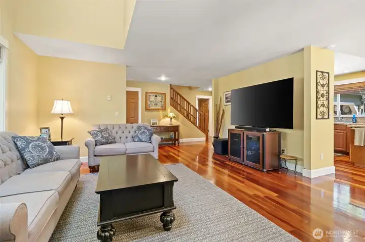 Looking back from the fireplace, the great room's open and versatile floor plan comes into view. The seamless flow between the living area, the central staircase, and the adjacent kitchen makes this home perfect for entertaining.