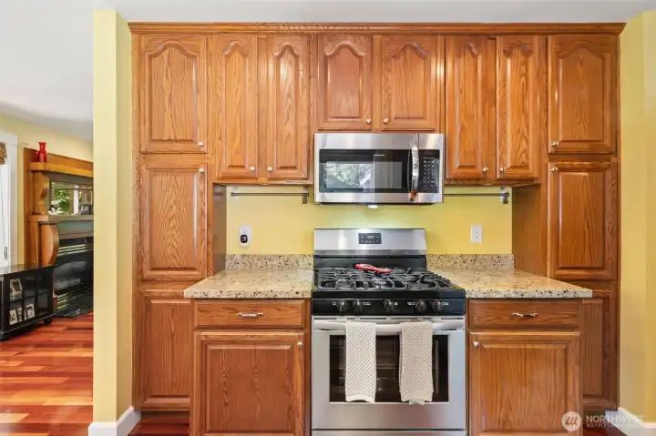 Abundant storage is a hallmark of this kitchen, showcased by the beautifully crafted, floor-to-ceiling oak cabinets surrounding the stainless steel gas range and microwave.