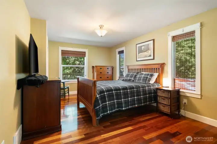 Retreat to a generous primary bedroom complete with stunning hardwood floors and multiple large windows that look out onto the peaceful, wooded surroundings. There is ample room for a complete king-size bedroom set and additional media or seating arrangements.