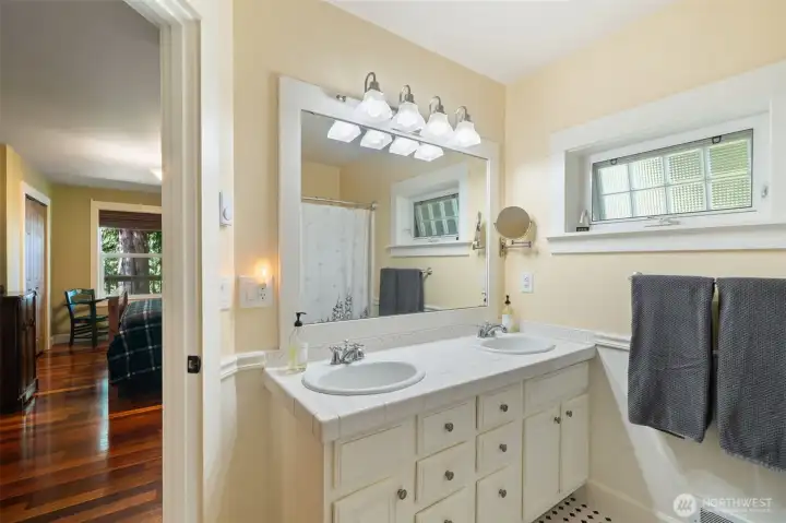 The primary bathroom offers great functionality with a spacious double-sink vanity, tile countertops, and classic wainscoting detail.
