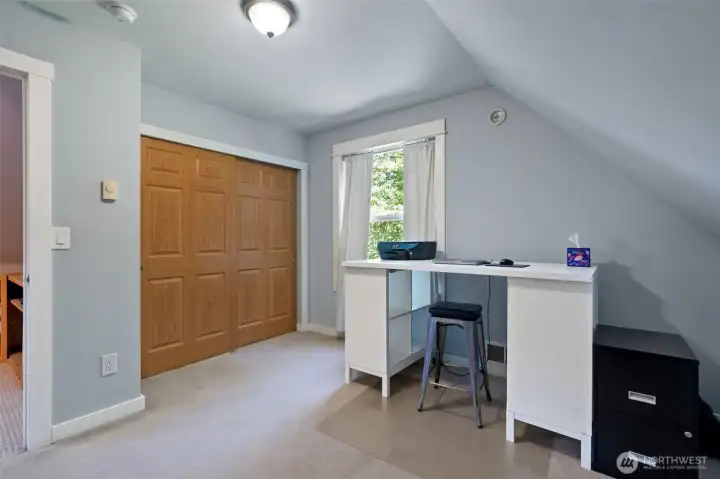 Another perspective of the upper-level office highlights its generous proportions and storage capacity. A large, double-door wood closet provides ample space for clothes or supplies