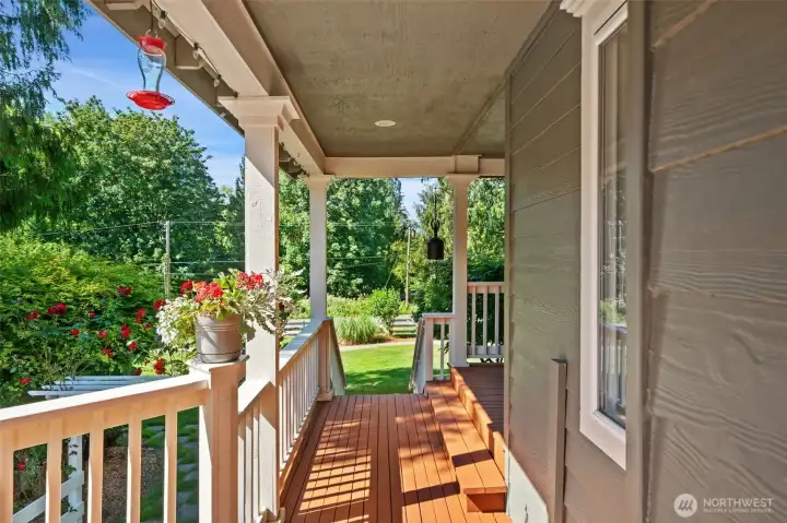 Looking down from the front steps, this view highlights the seamless transition from the porch to the home's vibrant outdoor spaces. Framed by mature roses and lush greenery, it's a serene, park-like setting