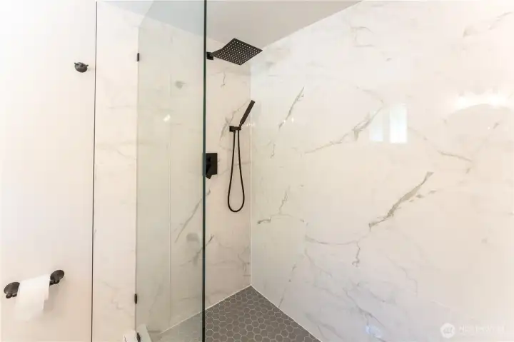 Large shower in primary bathroom with floor to ceiling tile and modern black fixtures