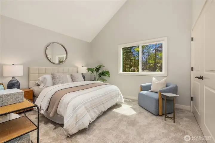 A peaceful main-level bedroom offers vaulted ceilings, soft natural light, and tranquil woodland views, creating a comfortable retreat for guests or everyday living. A peaceful main-level bedroom offers vaulted ceilings, soft natural light, and tranquil woodland views, creating a comfortable retreat for guests or everyday living.