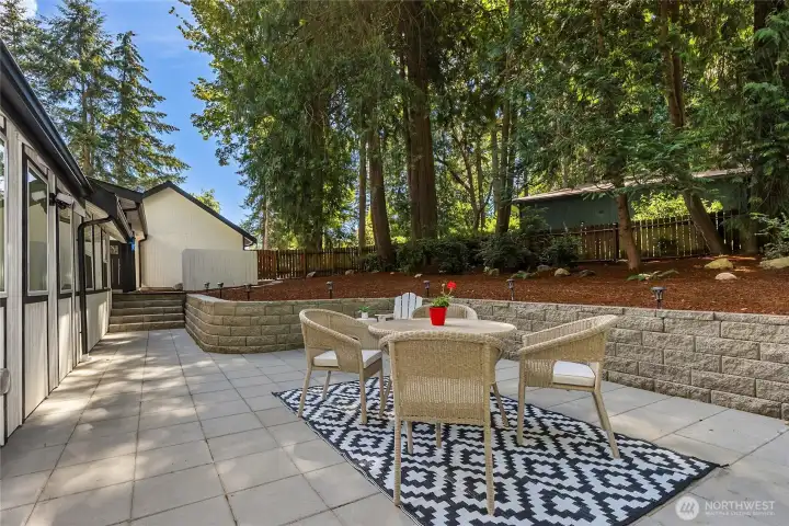 The expansive patio is perfectly positioned between the kitchen and sunroom, creating seamless indoor-outdoor living for effortless entertaining, alfresco dining, or simply relaxing beneath a canopy of majestic evergreens. The expansive patio is perfectly positioned between the kitchen and sunroom, creating seamless indoor-outdoor living for effortless entertaining, alfresco dining, or simply relaxing beneath a canopy of majestic evergreens.
