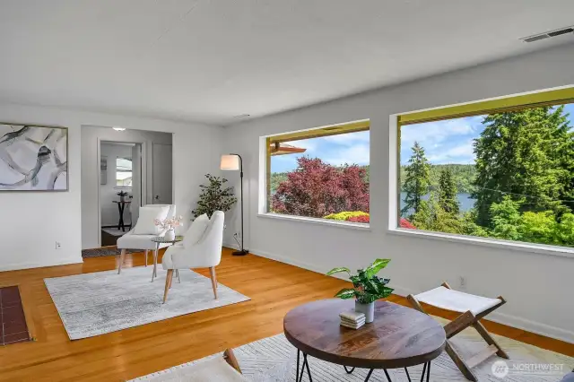The wall of windows continues in the spacious Living Room with warm hardwoods