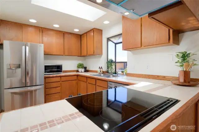 The light-filled kitchen hosts Stainless steel appliances, glass cooktop and garden window.